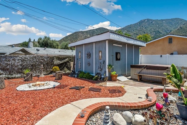 33206 Churchill St, Lake Elsinore, CA 92530 - fenced backyard with a hot tub, a mountain view, an outdoor structure, and a fire pit