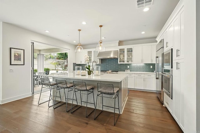 939 Moonstone Ct, Encinitas, CA 92024 - kitchen with exhaust hood, light countertops, a kitchen bar, decorative backsplash, and recessed lighting