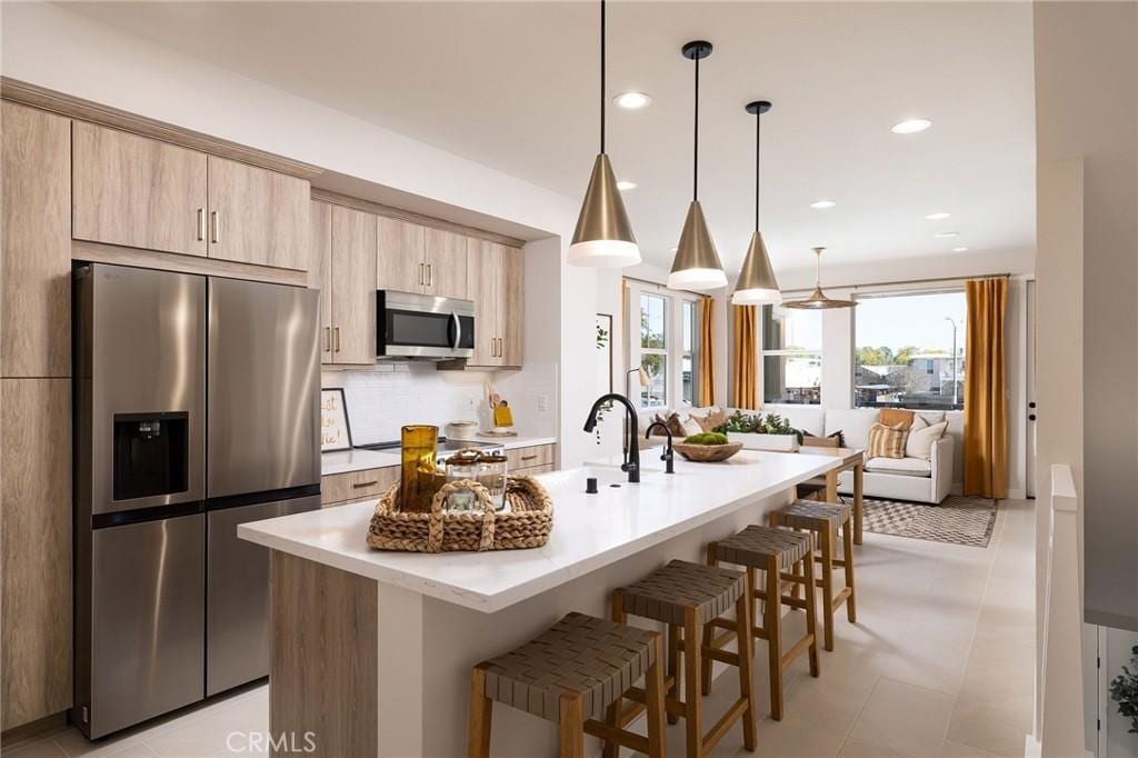 119 N First Ave, Upland, CA 91786 - kitchen with stainless steel appliances, a kitchen bar, light countertops, an island with sink, and light brown cabinets