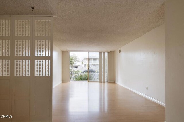 1000 Cordova St Unit 103, Pasadena, CA 91106 - empty room featuring a textured ceiling, baseboards, a wall of windows, and wood finished floors