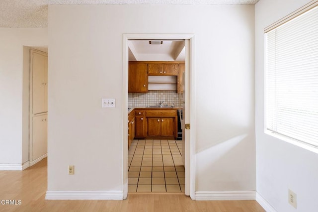 1000 Cordova St Unit 103, Pasadena, CA 91106 - kitchen featuring a sink, tasteful backsplash, brown cabinets, light wood-style flooring, and baseboards
