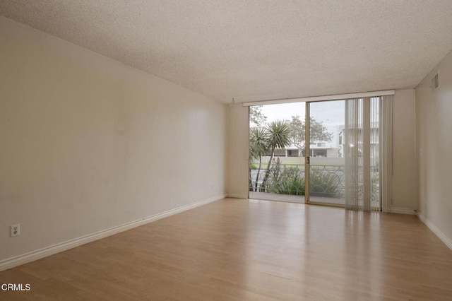 1000 Cordova St Unit 103, Pasadena, CA 91106 - empty room featuring light wood-style flooring, expansive windows, a textured ceiling, and baseboards