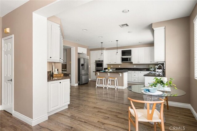 2437 N Eaton Ct, Orange, CA 92867 - kitchen with stainless steel appliances, dark countertops, a kitchen island, white cabinetry, and recessed lighting