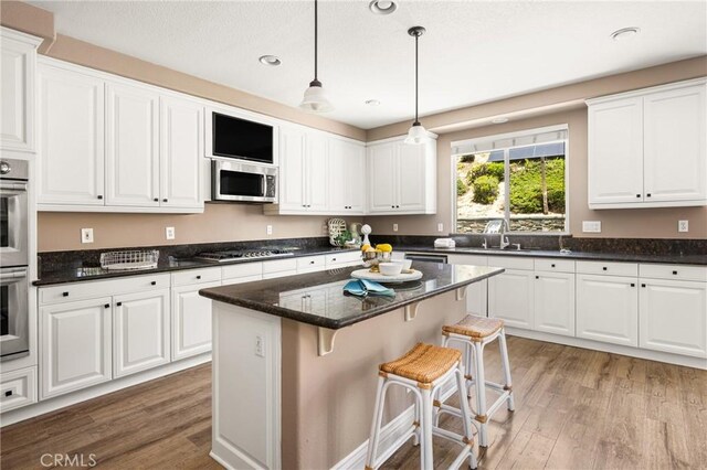 2437 N Eaton Ct, Orange, CA 92867 - kitchen with appliances with stainless steel finishes, light wood-type flooring, white cabinetry, recessed lighting, and decorative light fixtures