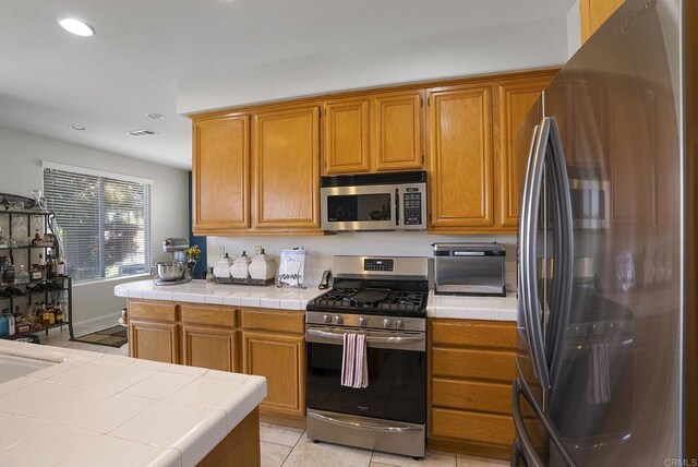 320 Corte Castillo, Chula Vista, CA 91914 - kitchen with appliances with stainless steel finishes, tile counters, recessed lighting, light tile patterned flooring, and brown cabinets