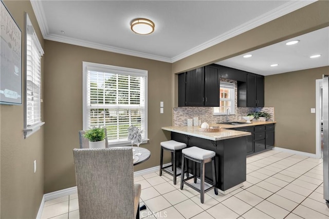 825 E Palm Ave, Monrovia, CA 91016 - kitchen featuring dark cabinetry, light countertops, a kitchen breakfast bar, plenty of natural light, and ornamental molding