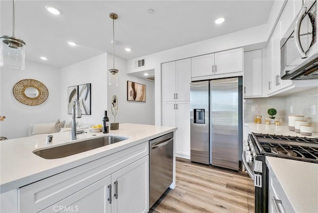 11047 Wander Dr, Rancho Cucamonga, CA 91730 - kitchen featuring stainless steel appliances, a sink, light countertops, white cabinetry, and decorative light fixtures