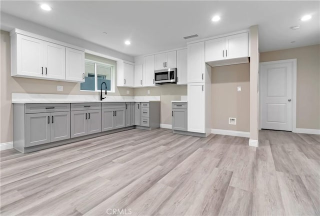 22022 Pioneer Blvd Unit A & B, Hawaiian Gardens, CA 90716 - kitchen featuring stainless steel microwave, gray cabinets, light wood finished floors, white cabinets, and recessed lighting