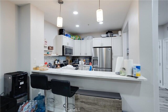 12668 Chapman Ave Unit 2108, Garden Grove, CA 92840 - kitchen featuring stainless steel appliances, a peninsula, decorative backsplash, pendant lighting, and white cabinets
