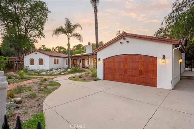 1247 Journeys End Dr, La Canada Flintridge, CA 91011 - mediterranean / spanish house with an attached garage, a chimney, stucco siding, and concrete driveway