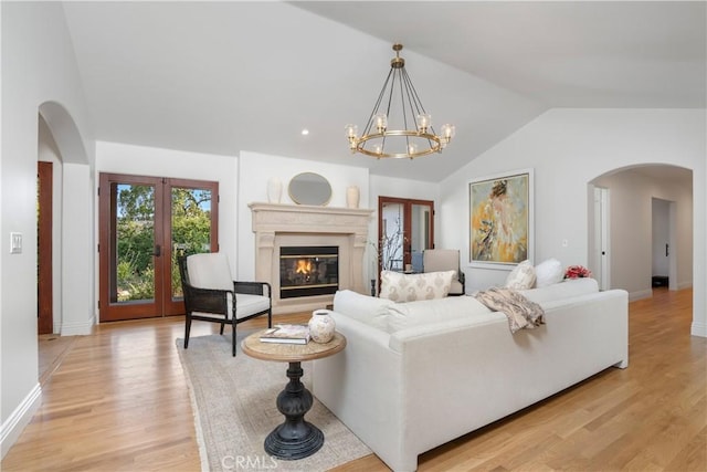 1247 Journeys End Dr, La Canada Flintridge, CA 91011 - living area featuring arched walkways, vaulted ceiling, light wood-type flooring, a glass covered fireplace, and a chandelier