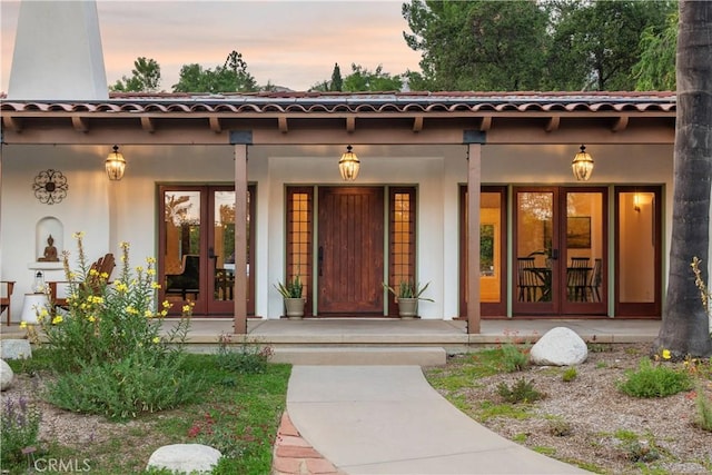 1247 Journeys End Dr, La Canada Flintridge, CA 91011 - exterior entry at dusk featuring french doors, a porch, and stucco siding