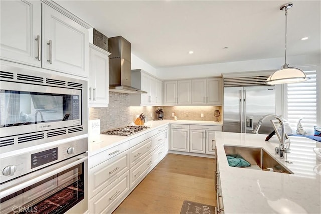 2393 Ocean St, Carlsbad, CA 92008 - kitchen with built in appliances, wall chimney exhaust hood, a sink, white cabinetry, and decorative backsplash