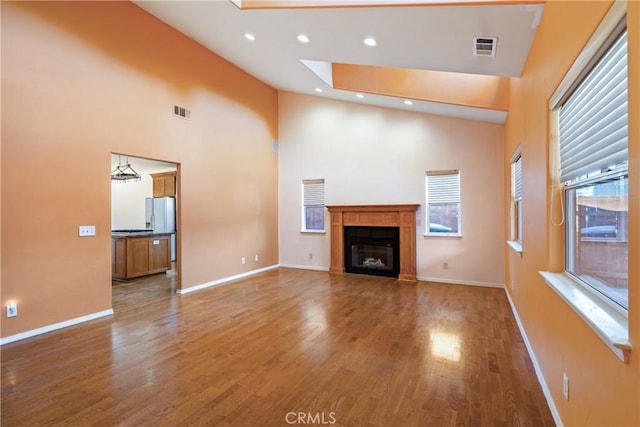1550 Strawberry Ave, Arroyo Grande, CA 93420 - unfurnished living room with a towering ceiling, wood finished floors, baseboards, a glass covered fireplace, and recessed lighting