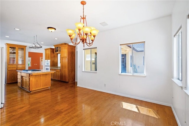 1550 Strawberry Ave, Arroyo Grande, CA 93420 - kitchen featuring a chandelier, brown cabinetry, double oven, a kitchen island, and wood finished floors