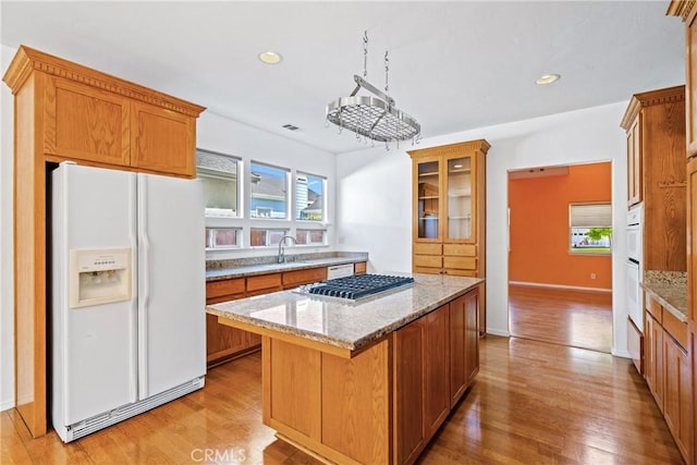 1550 Strawberry Ave, Arroyo Grande, CA 93420 - kitchen with white fridge with ice dispenser, stainless steel gas stovetop, glass insert cabinets, light stone countertops, and a kitchen island