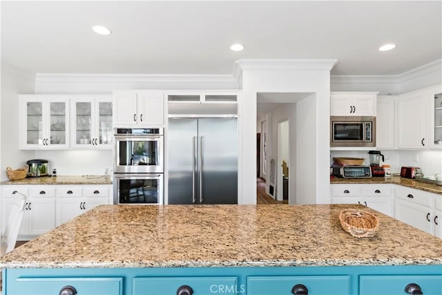 23556 Kathryn St, Murrieta, CA 92562 - kitchen with built in appliances, ornamental molding, light stone counters, white cabinets, and glass insert cabinets