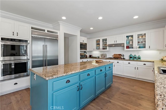 23556 Kathryn St, Murrieta, CA 92562 - kitchen featuring built in appliances, blue cabinetry, under cabinet range hood, white cabinetry, and ornamental molding