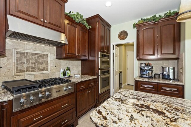 14160 Vai Brothers Dr, Rancho Cucamonga, CA 91739 - kitchen with under cabinet range hood, appliances with stainless steel finishes, decorative backsplash, light stone countertops, and light tile patterned flooring