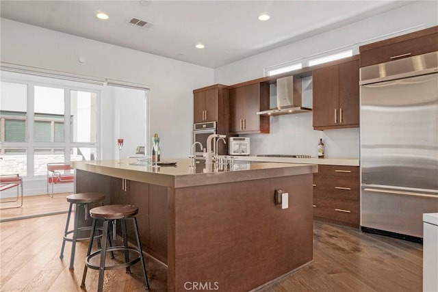 5823 Seahorse Ct, Playa Vista, CA 90094 - kitchen featuring stainless steel built in refrigerator, wall chimney exhaust hood, wood finished floors, a breakfast bar, and recessed lighting