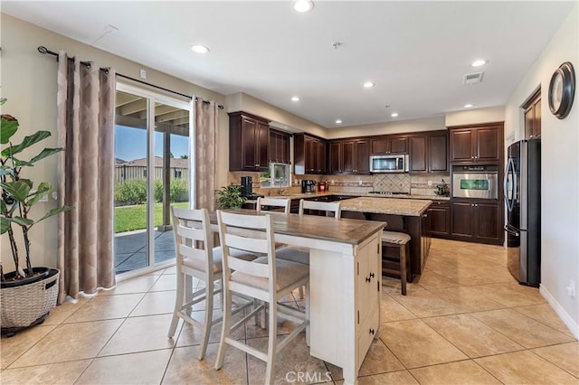 12178 Scenic Vw, Riverside, CA 92505 - kitchen featuring black appliances, a kitchen island, light tile patterned floors, a kitchen bar, and decorative backsplash