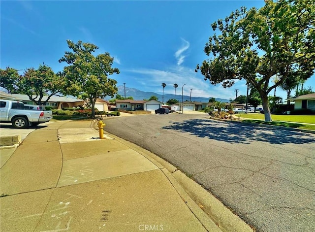 7534 Layton St, Rancho Cucamonga, CA 91730 - view of asphalt road with curbs, sidewalks, a residential view, and a mountain view