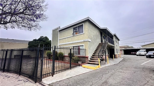 10241 Ruoff Ave, Whittier, CA 90604 - view of front of property with stairway, stucco siding, and a parking lot
