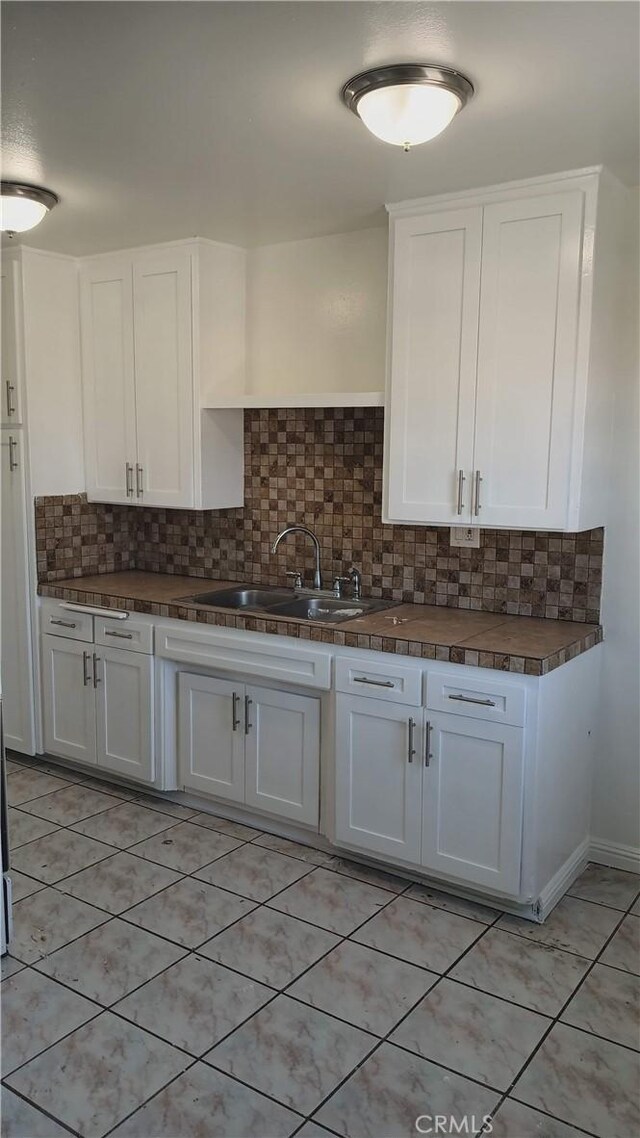 10241 Ruoff Ave, Whittier, CA 90604 - kitchen featuring a sink, white cabinets, tasteful backsplash, and light tile patterned floors