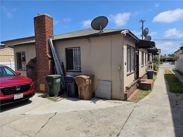 1609 W 107th St, County Los Angeles, CA 90047 - view of side of home with stucco siding and a chimney