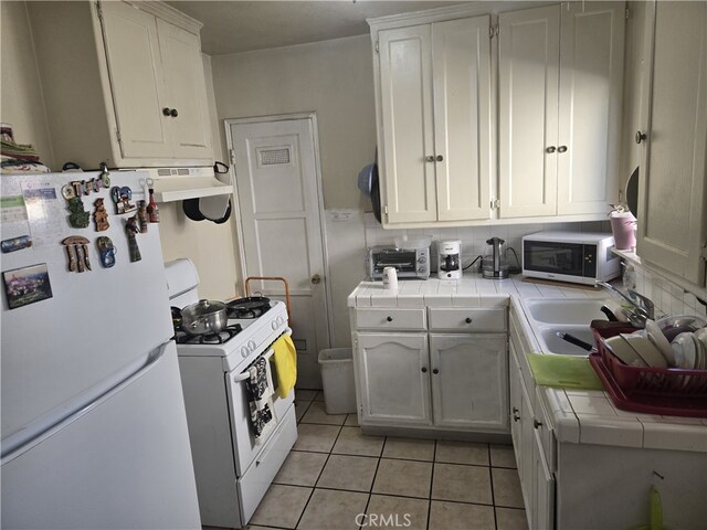 1609 W 107th St, County Los Angeles, CA 90047 - kitchen featuring white appliances, tile counters, light tile patterned floors, and white cabinets