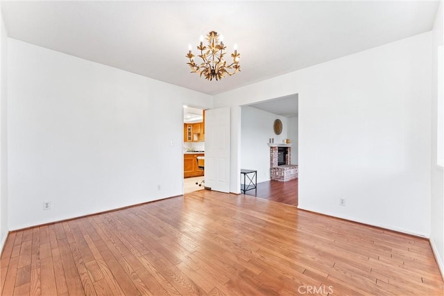 9818 Capulet Ave, Whittier, CA 90603 - spare room with a chandelier, light wood-style flooring, and a fireplace