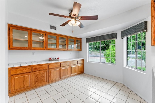 9818 Capulet Ave, Whittier, CA 90603 - kitchen featuring brown cabinets, glass insert cabinets, tile counters, and ceiling fan