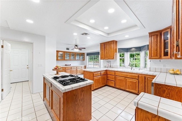 9818 Capulet Ave, Whittier, CA 90603 - kitchen with black gas cooktop, recessed lighting, light tile patterned floors, a peninsula, and brown cabinetry