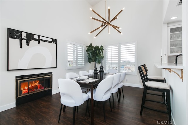 1617 S Beverly Glen Blvd Unit 301, Los Angeles, CA 90024 - dining room with wood finished floors, a chandelier, baseboards, a high ceiling, and a glass covered fireplace