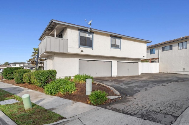 3468 Los Mochis Way, Oceanside, CA 92056 - view of side of home featuring a garage, stucco siding, stairway, and asphalt driveway