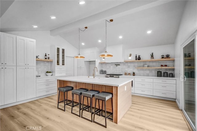 2842 E Virginia Ave, Anaheim, CA 92806 - kitchen featuring open shelves, backsplash, light wood-style flooring, light countertops, and a breakfast bar