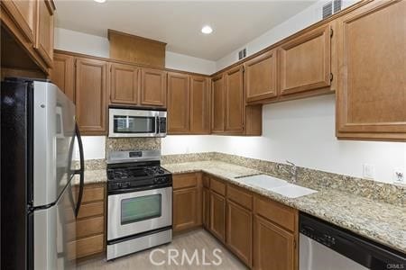 4304 Owens St Unit 102, Corona, CA 92883 - kitchen with appliances with stainless steel finishes, light stone counters, recessed lighting, and brown cabinets