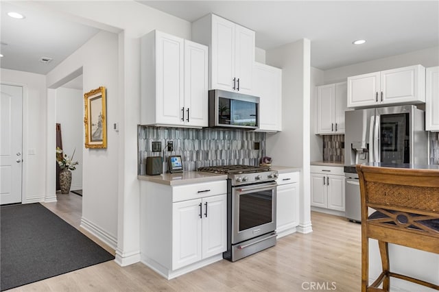 36275 Firelight Cir, Wildomar, CA 92595 - kitchen featuring appliances with stainless steel finishes, decorative backsplash, light wood-type flooring, recessed lighting, and white cabinetry