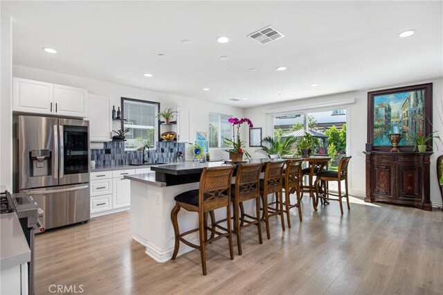 36275 Firelight Cir, Wildomar, CA 92595 - kitchen featuring stainless steel appliances, a breakfast bar, light wood-type flooring, white cabinets, and backsplash