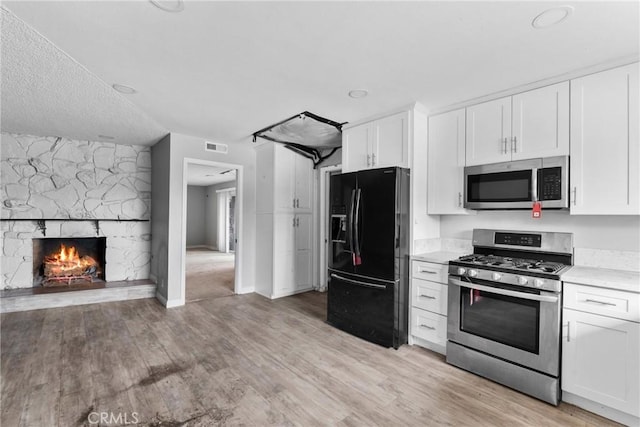 1754 N 1st Ave, Upland, CA 91784 - kitchen with stainless steel appliances, white cabinetry, light wood-type flooring, and a fireplace