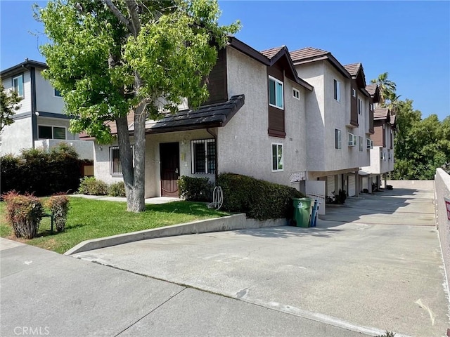 428 N Chapel Ave Unit B, Alhambra, CA 91801 - view of front of home featuring stucco siding, a garage, a residential view, asphalt driveway, and a front lawn