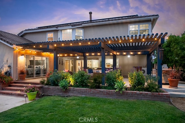 19520 Bermudas St, Porter Ranch, CA 91326 - back of property at dusk featuring a pergola, stucco siding, a yard, and a patio area