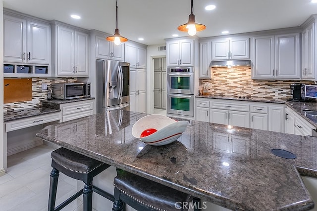 19520 Bermudas St, Porter Ranch, CA 91326 - kitchen featuring stainless steel appliances, backsplash, under cabinet range hood, a breakfast bar area, and pendant lighting