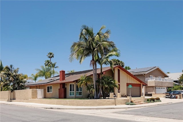 24711 Eloisa Dr, Mission Viejo, CA 92691 - view of front facade with roof mounted solar panels, a chimney, concrete driveway, and a garage