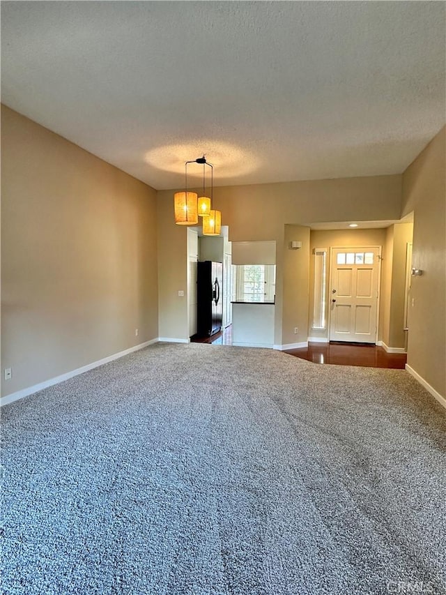25843 Mcbean Unit 9, Valencia, CA 91355 - unfurnished living room featuring dark colored carpet, a textured ceiling, and baseboards