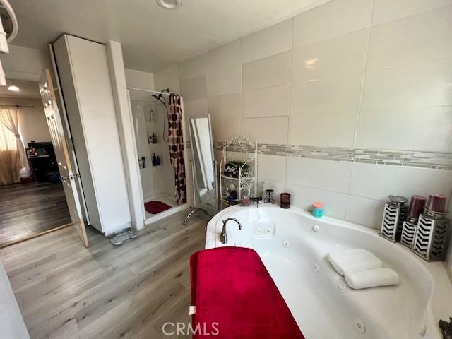24910 Allesandro, Moreno Valley, CA 92553 - bathroom with a stall shower, tile walls, wood finished floors, and a jetted tub