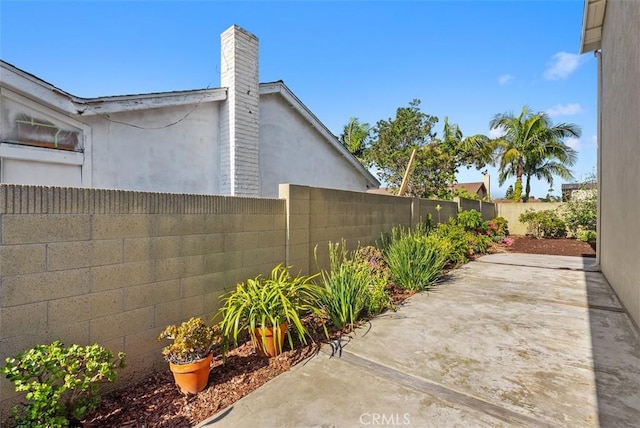 21692 Seaside Ln, Huntington Beach, CA 92646 - view of home's exterior featuring a fenced backyard, a patio, stucco siding, and a chimney