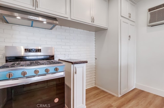 117 E 229th Pl, Carson, CA 90745 - kitchen with stainless steel gas range oven, range hood, light wood-type flooring, a wall mounted AC, and backsplash