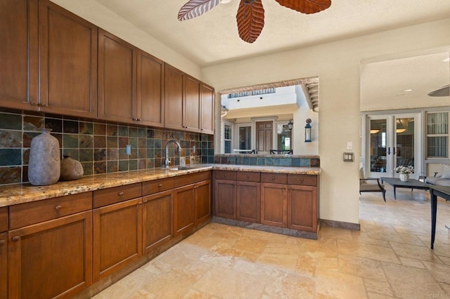 6937 Corte Langosta, Carlsbad, CA 92009 - kitchen with a sink, ceiling fan, stone tile flooring, tasteful backsplash, and brown cabinetry