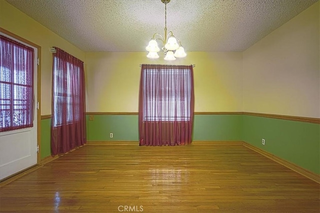 5062 Magnolia Ave, Riverside, CA 92506 - empty room with a chandelier, hardwood / wood-style floors, a textured ceiling, and baseboards